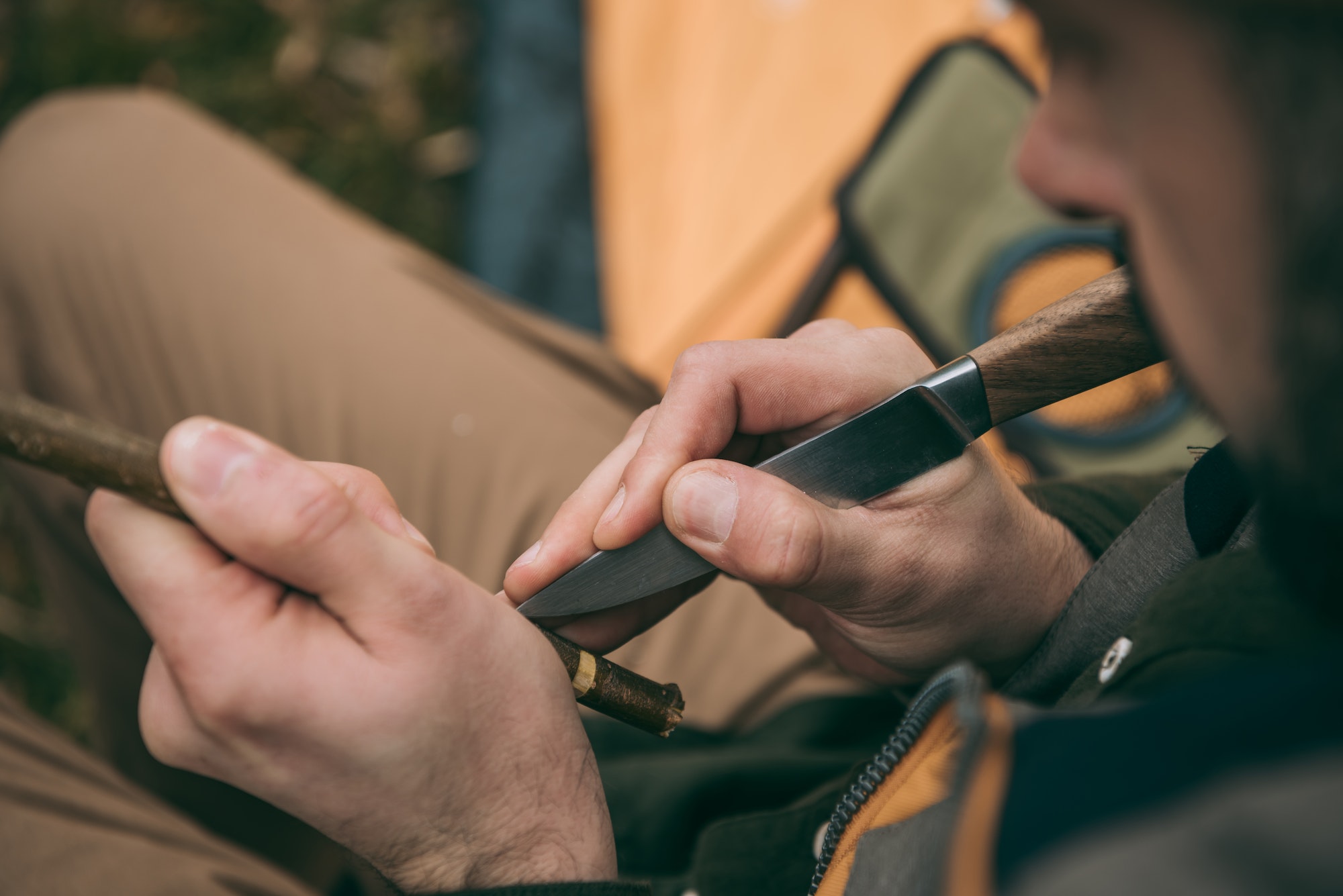 Handsome man sharpening a branch for camping