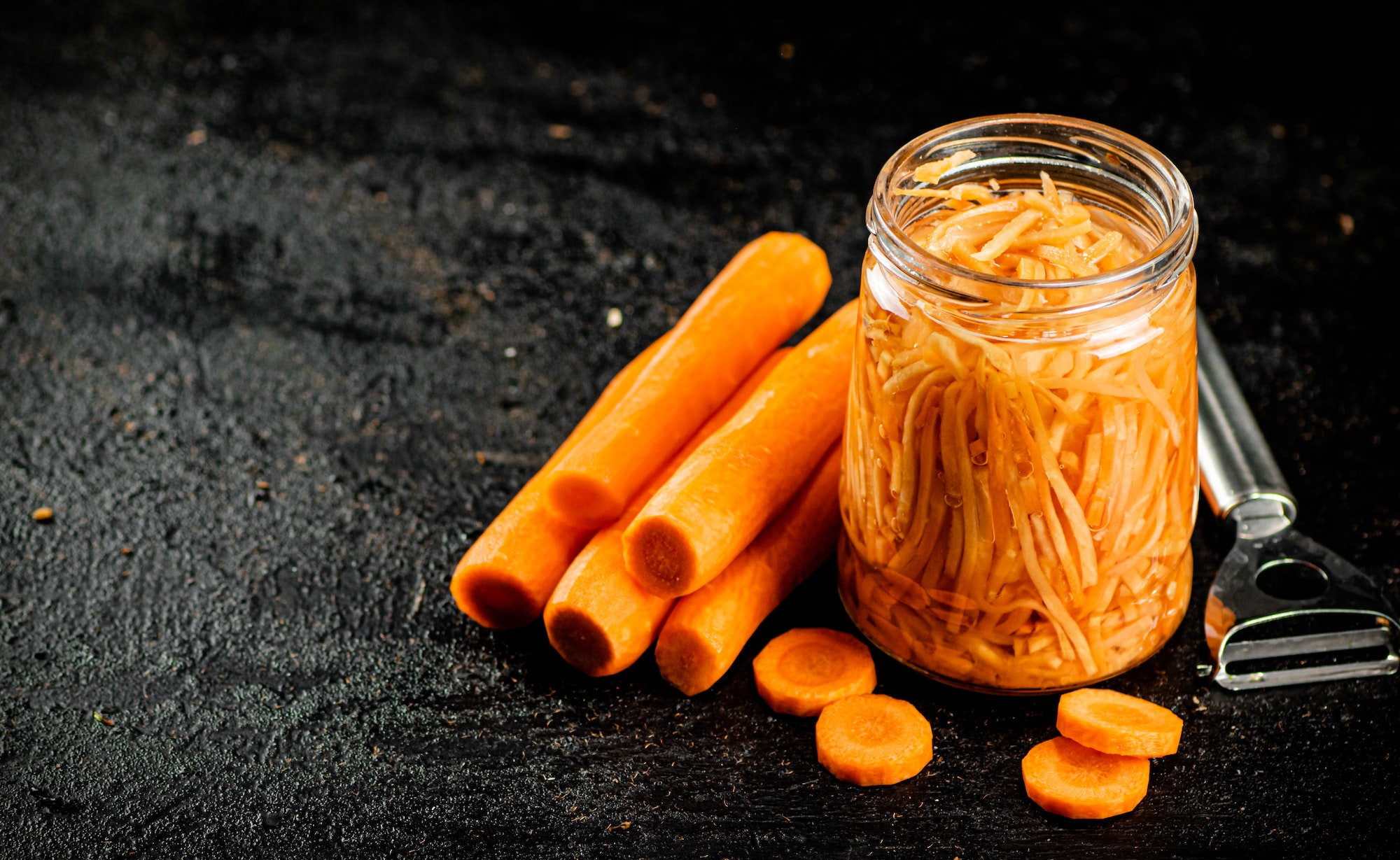 A glass jar with canned carrots.