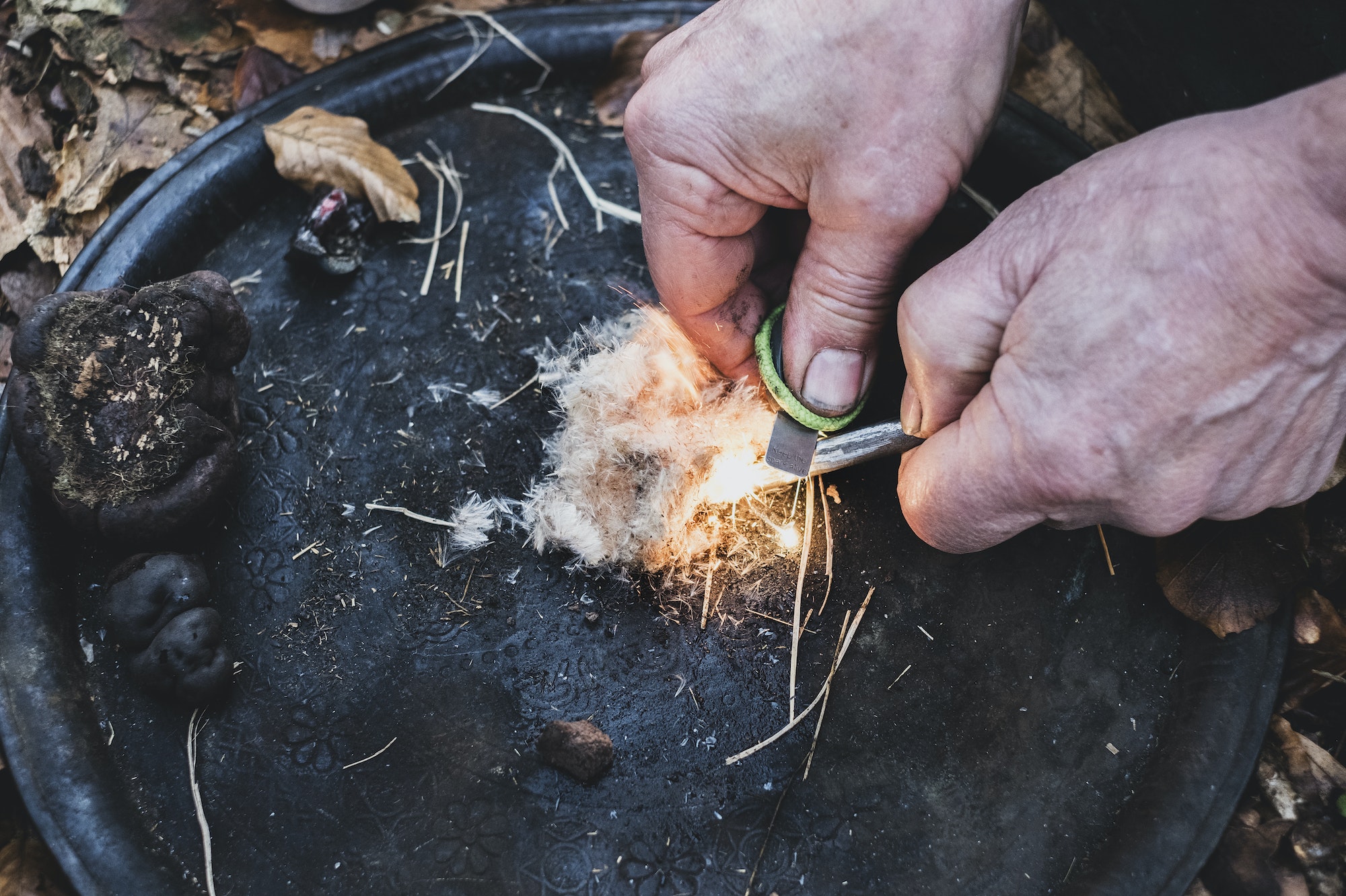 High angle close up of person igniting tinder to start a campfire.